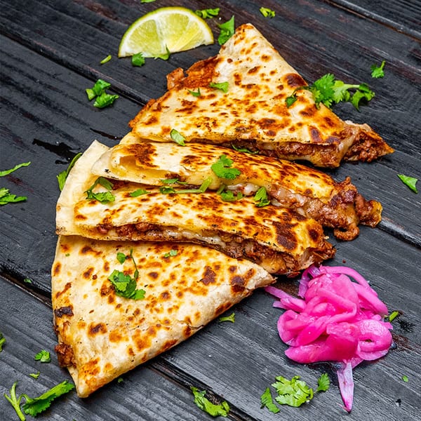 Three Tiagos Tacos quesadillas with meat and cheese, garnished with cilantro, lime, and pickled onions.